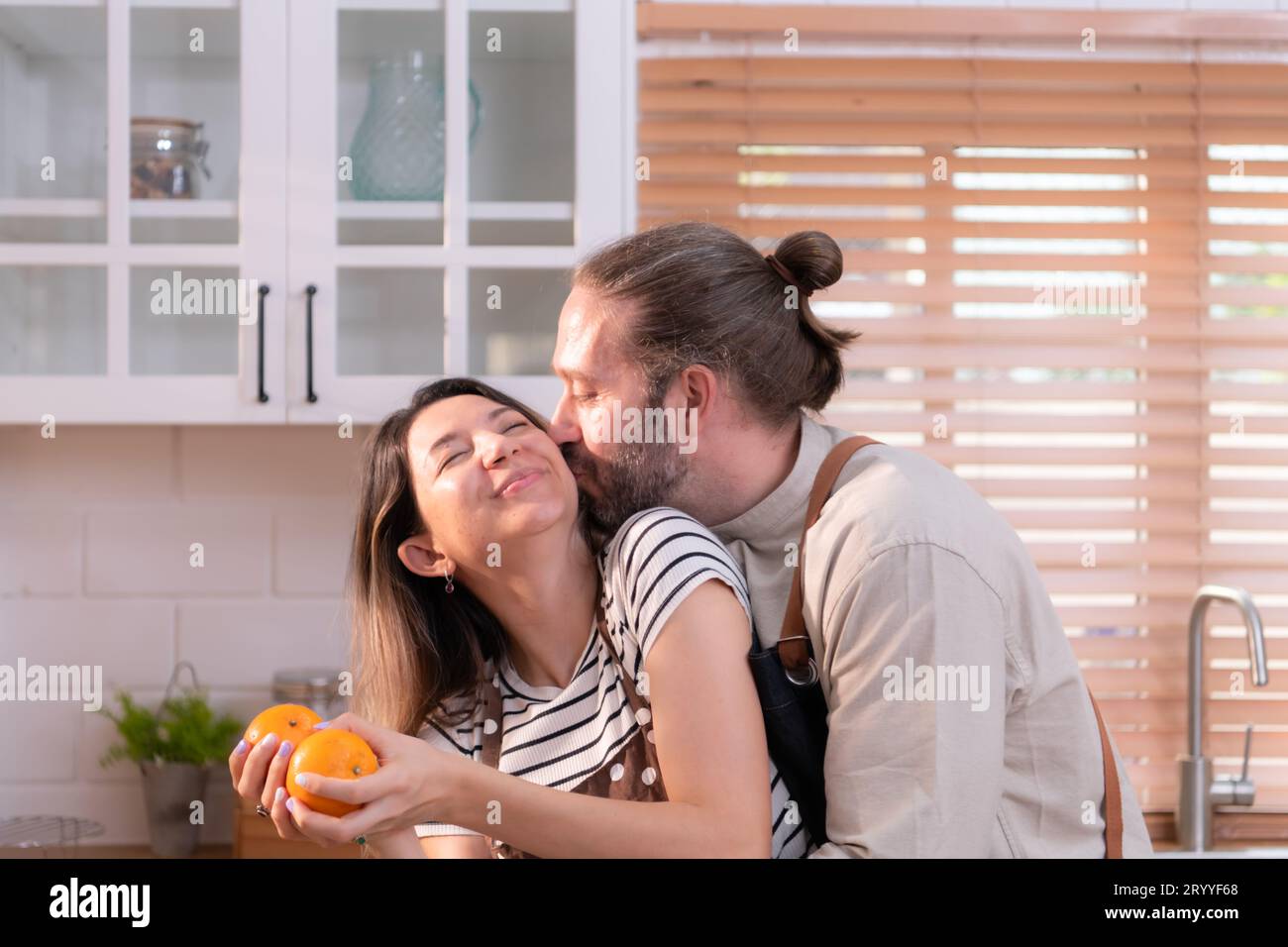 Vater und Mutter in der Küche des Hauses machen es gut, zusammen zu essen, während sie auf die Rückkehr des Jungen warten Stockfoto