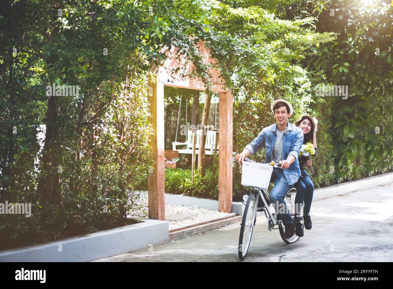 Glückliches Paar, das gemeinsam Fahrrad fährt, im Hintergrund des romantischen Aussichtsparks. Valentinstag und Hochzeitsreise-Konzept. Personen und Stockfoto