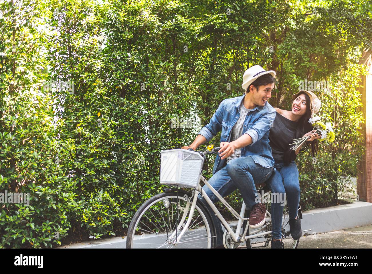 Glückliches Paar, das gemeinsam Fahrrad fährt, im Hintergrund des romantischen Aussichtsparks. Valentinstag und Hochzeitsreise-Konzept. Personen und Stockfoto
