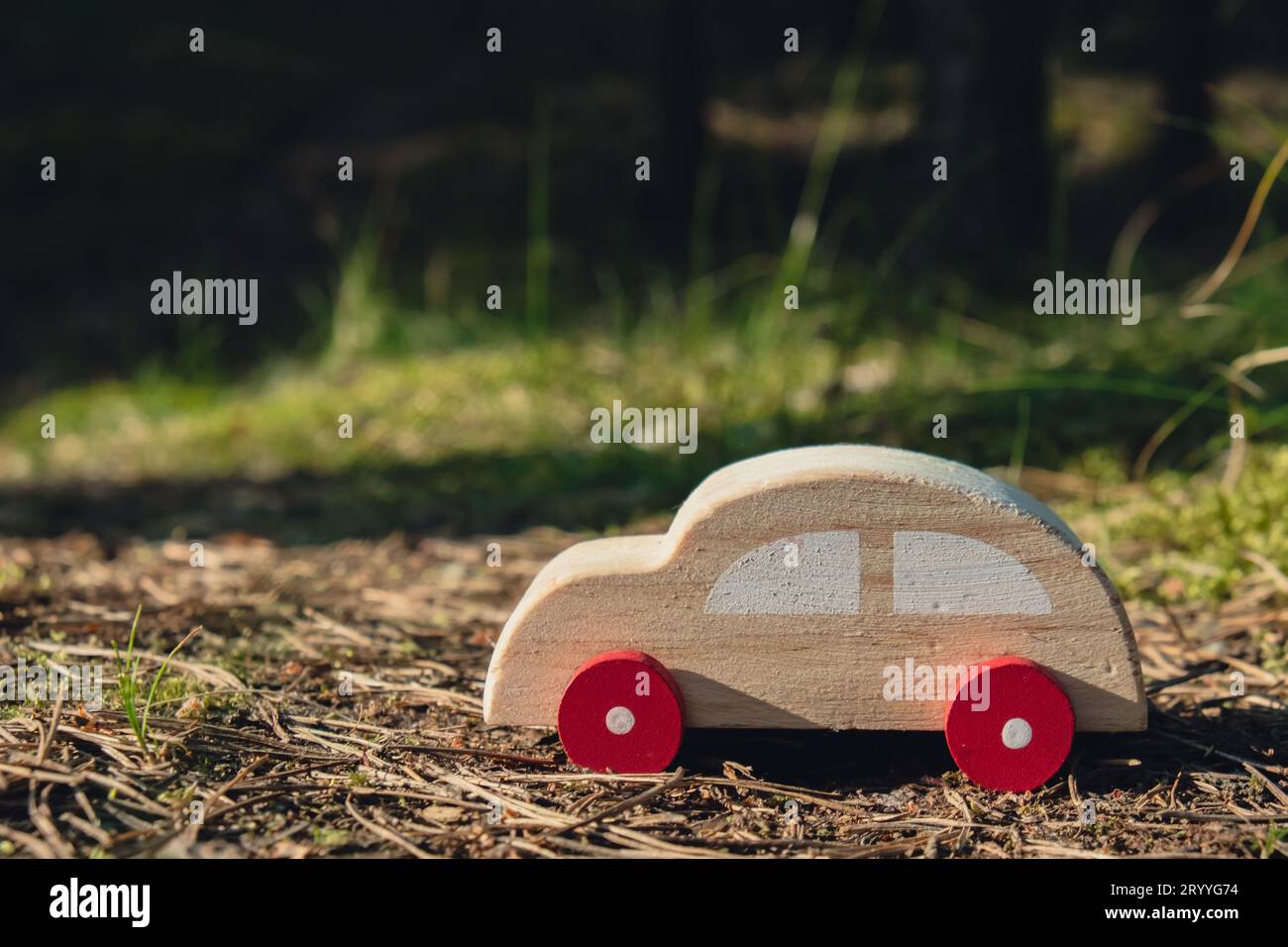 Hölzernes Spielzeugauto auf grünem Waldhintergrund. ECO-Car Concept Weltweit autofreier Tag Elektrofahrzeug Umwelt Automobil Transpo Stockfoto
