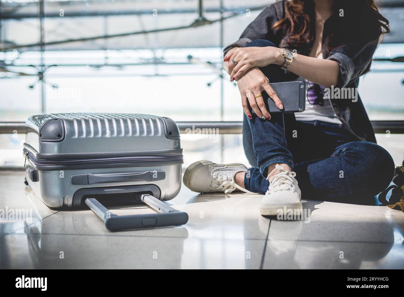 Nahaufnahme einer jungen Frau mit Tasche und Koffer, die auf den Abflug wartet, während sie in der Flughafenlounge sitzt. Weibliche Reisende und Stockfoto