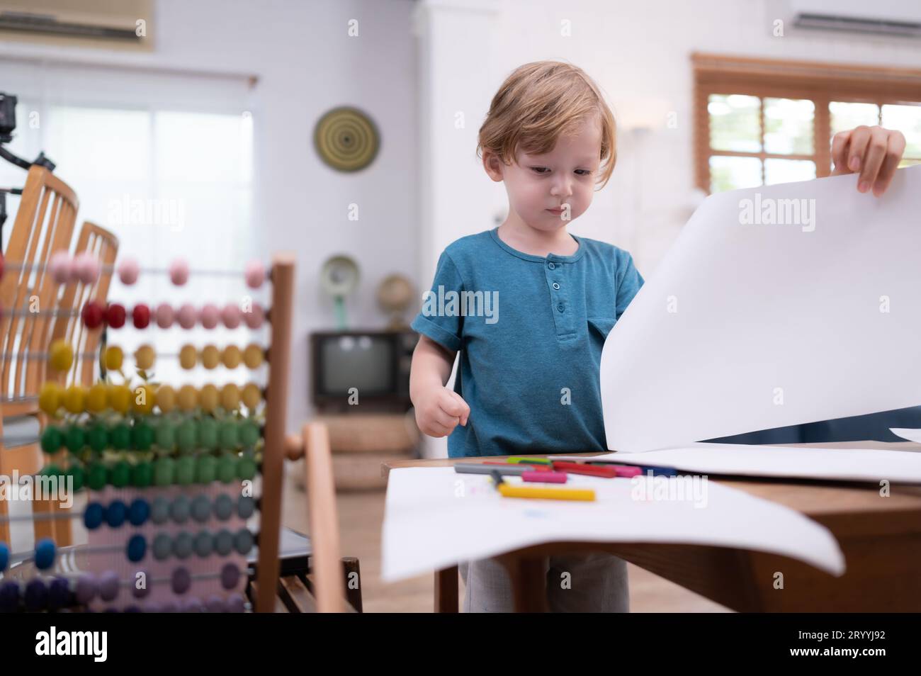 Die Vorstellungskraft eines kleinen Kindes wird durch farbige Bleistiftzeichnungen dargestellt, wobei die Mutter die Livi aufmerksam überwacht Stockfoto