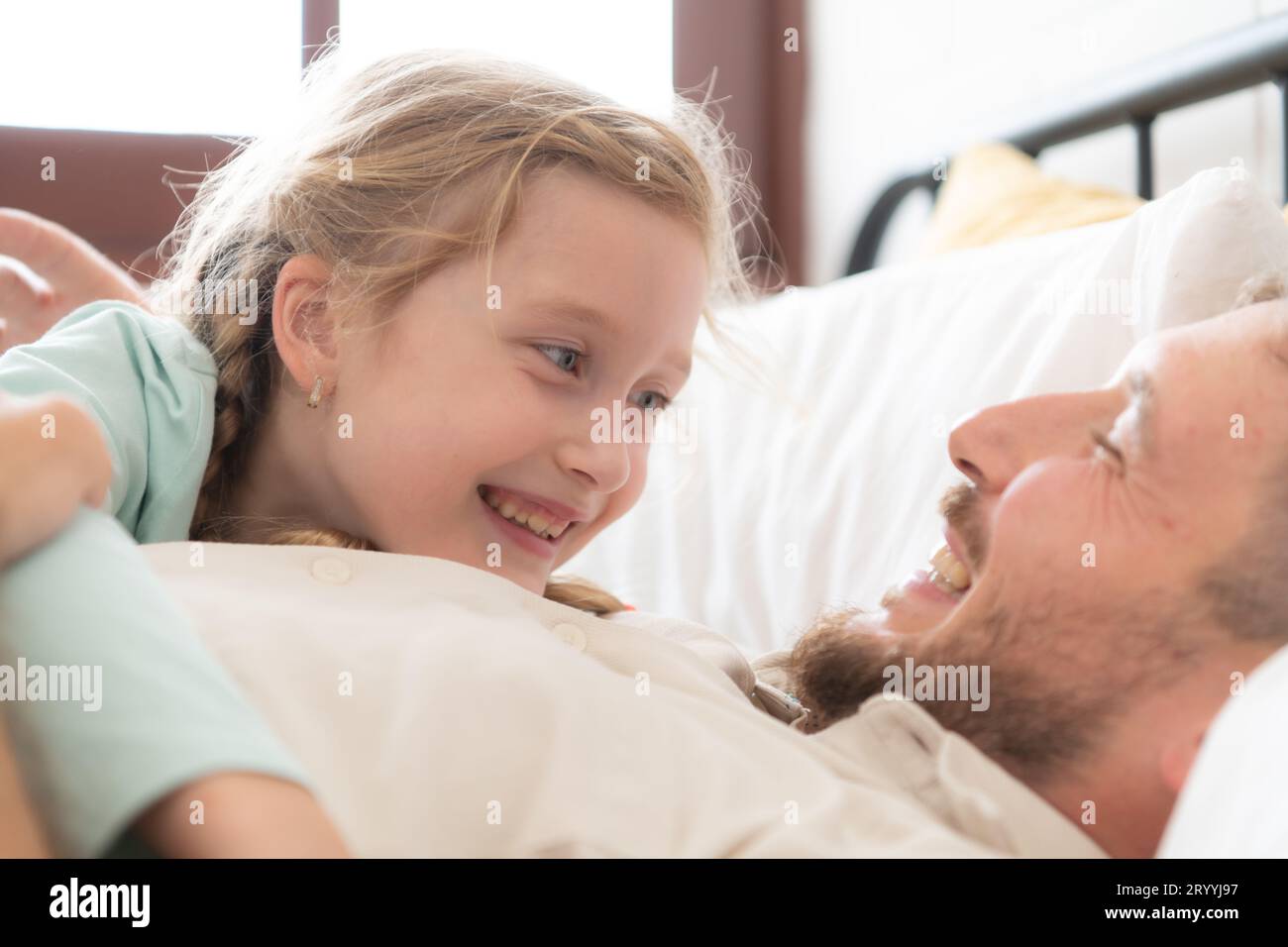 Ein Vater spricht gern mit seiner Tochter in seinem Schlafzimmer. Bevor er sich verabschiedet und ihre Tochter ins Bett schickt Stockfoto