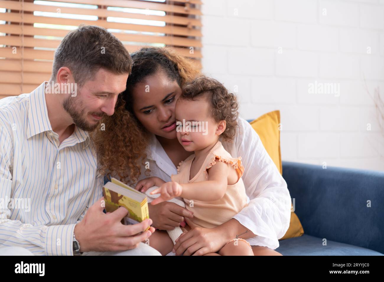 Eltern und Kinder entspannen sich im Wohnzimmer des Hauses. Beobachten Sie, wie Ihr Baby mit seinem Lieblingsspielzeug spielt. Stockfoto