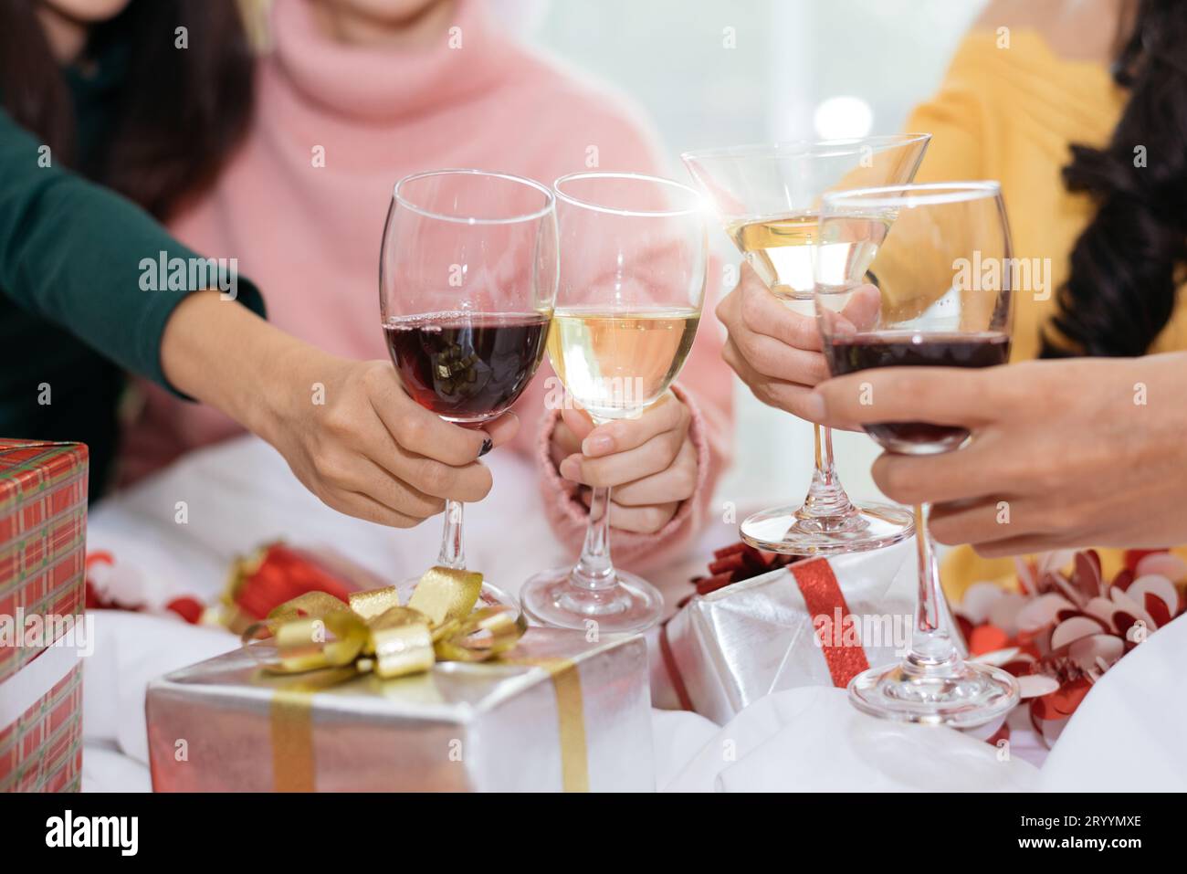 Hände von Menschen, die Neujahrsfeier zu Hause mit Weintrinkgläsern und modernem Hintergrund feiern. Neujahr und Weihnachten Par Stockfoto