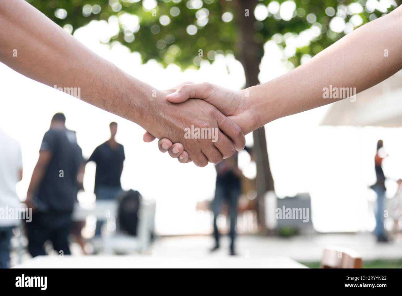 Geschlossen, der die Hand schütteln mit Menschen im Hintergrund. Geschäftliche Zusammenarbeit und Einheit Konzept. Business- und Außenbereich Thema. Stockfoto
