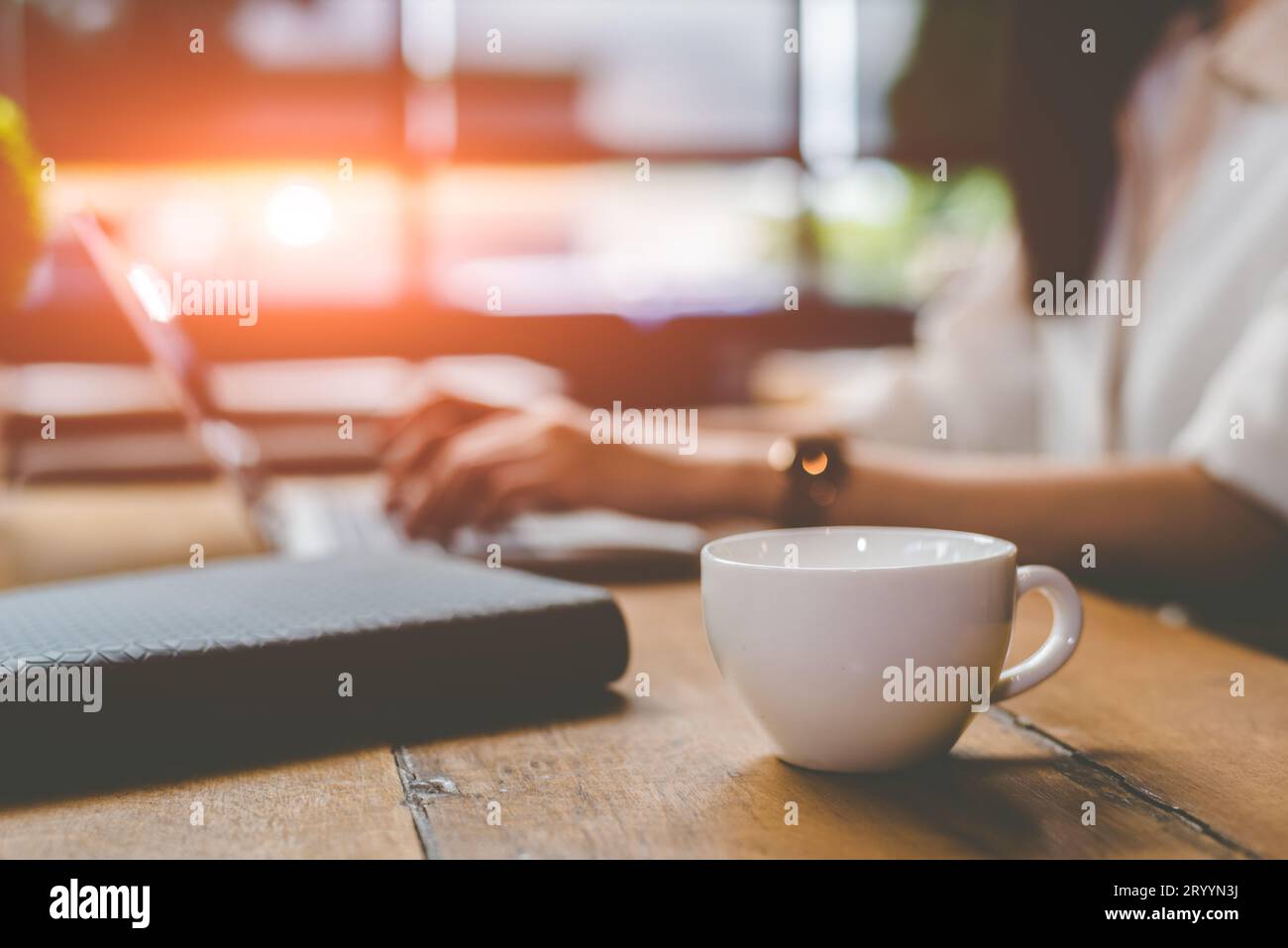 Nahaufnahme einer Kaffeetasse mit Geschäftsfrau, die im Außenbüro mit Laptop-Hintergrund arbeitet. Das Konzept der Menschen und Lebensstile. Busi Stockfoto