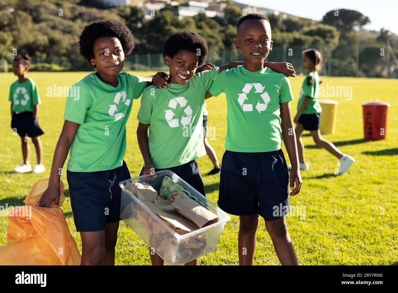 Porträt afroamerikanischer Jungen, die Recycling-Sammlung auf einem sonnigen Grundschulfeld Stockfoto