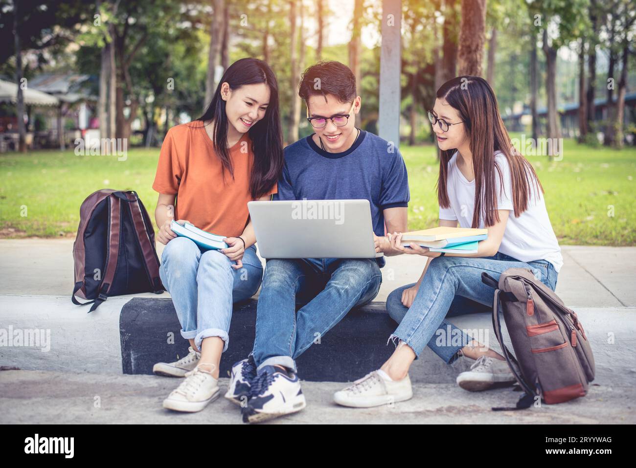 Drei junge asiatische Campus-Studenten genießen es, gemeinsam Nachhilfe zu geben und Bücher zu lesen. Freundschaft und Bildungskonzept. Campus-Schule und Stockfoto