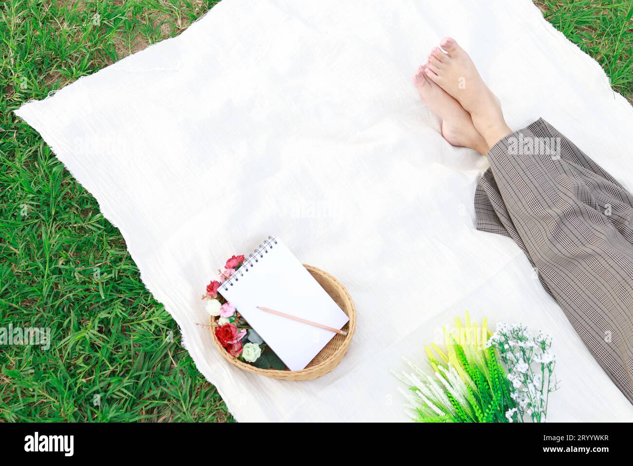 Frau allein, die sich am sonnigen Tag auf einem Picknick im Naturpark ausruht und den Sommer genießt und träumt Stockfoto