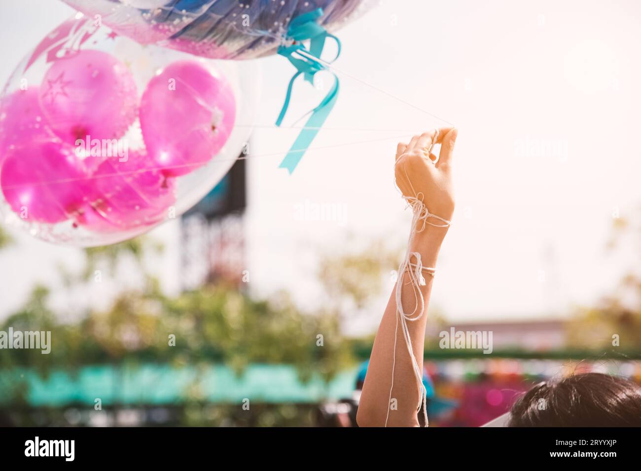 Hand hält das Seil des Begrüßungsballons für besondere Veranstaltungen oder Geburtstagsfeiern. Glücks- und Feierparty-Konzept. Friendshi Stockfoto