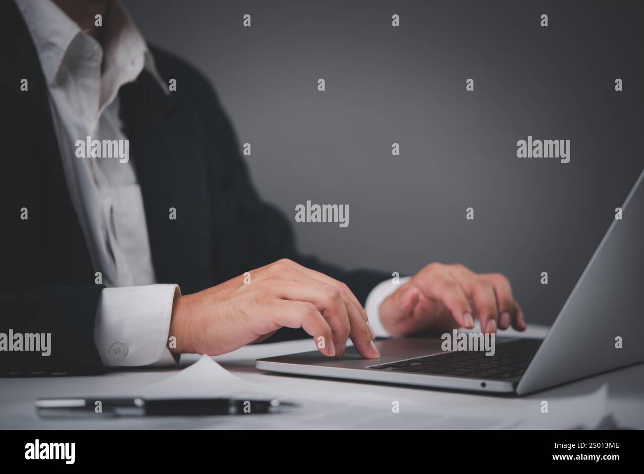 Geschäftsmann in formellem Anzug, der auf einem Laptop schreibt, konzentriert und produktiv bei der Arbeit. Ideal für Unternehmen, Unternehmergeist, Fernarbeit und Geschäftsumgebungen Stockfoto