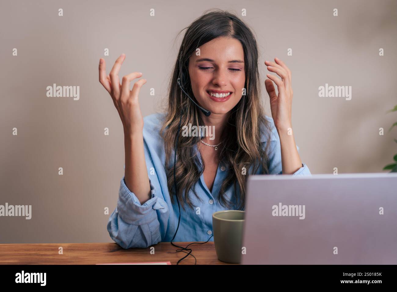Eine junge Frau, die ein Headset trägt, lächelt, während sie von zu Hause aus einen Videoanruf führt. Moderne Kommunikationstechnik in einem ungezwungenen Arbeitsumfeld. Stockfoto