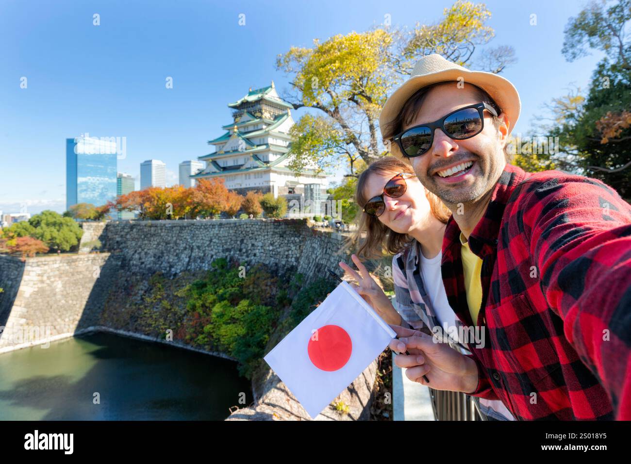 Ein junges Touristenpaar, das ein Selfie mit japanischer Flagge auf Osaka Castle macht, ist Osaka Castle eines der berühmtesten Wahrzeichen in Japan und Osaka, Urlaub Stockfoto