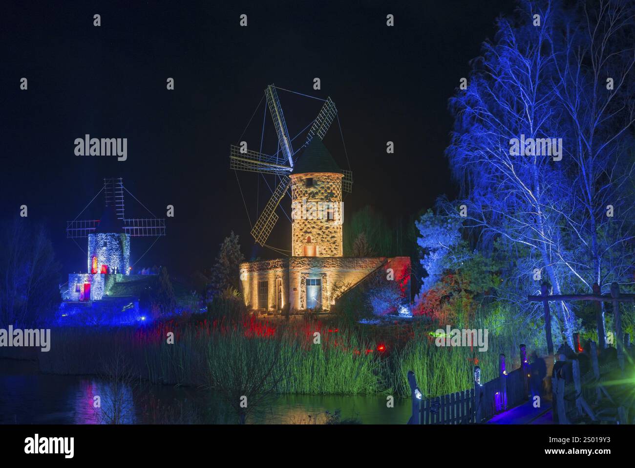 Zwei Windmühlen in einer nächtlichen Szene, beleuchtet mit bunten Lichtern und umgeben von Wasser, Welt der Lichter, Beleuchtung, Mühlenmuseum, Gifhorn, Lo Stockfoto