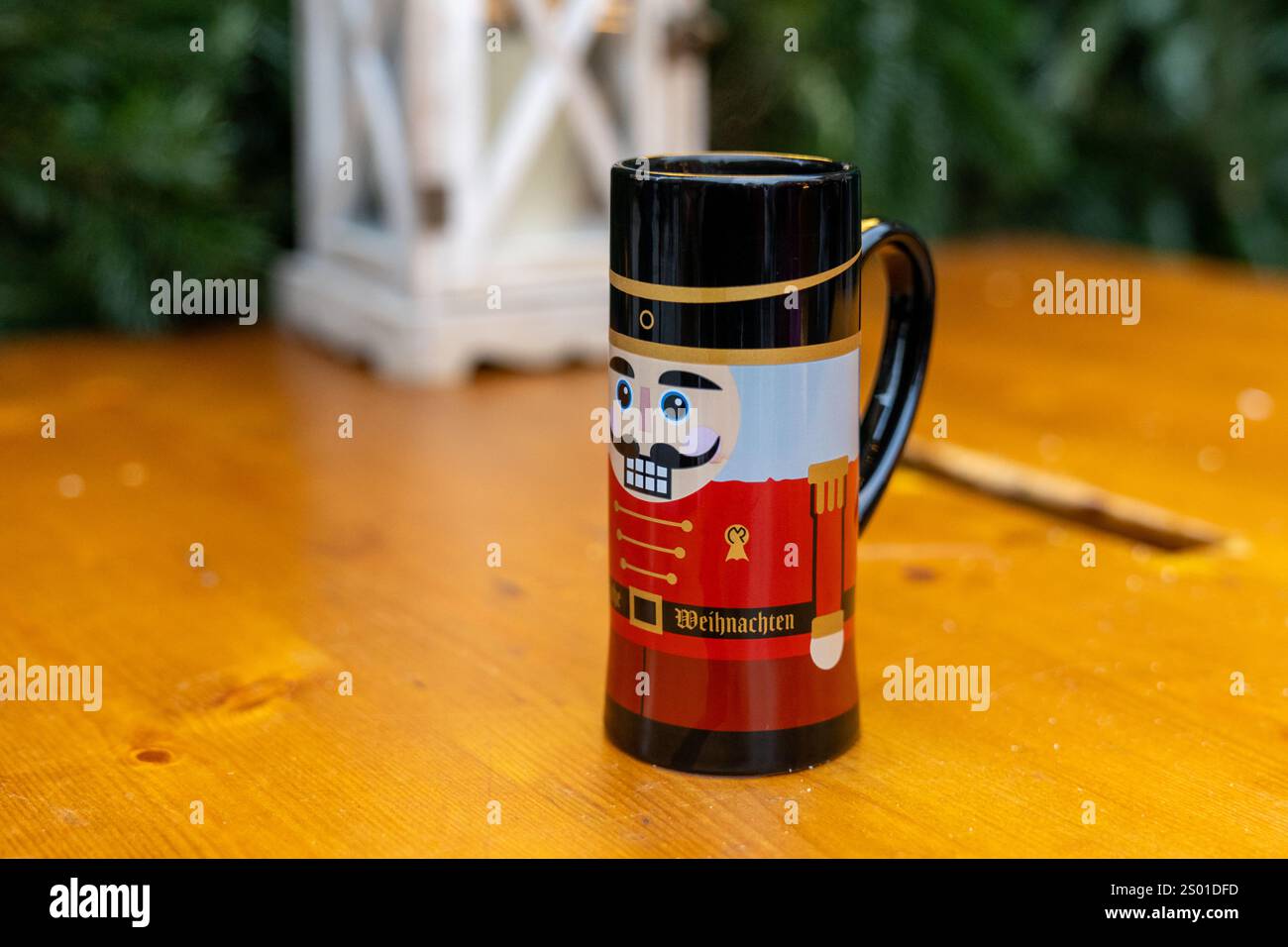 Niedlicher Nussknacker-Becher von einem Weihnachtsmarkt sitzt auf einem Holztisch, München Deutschland Stockfoto