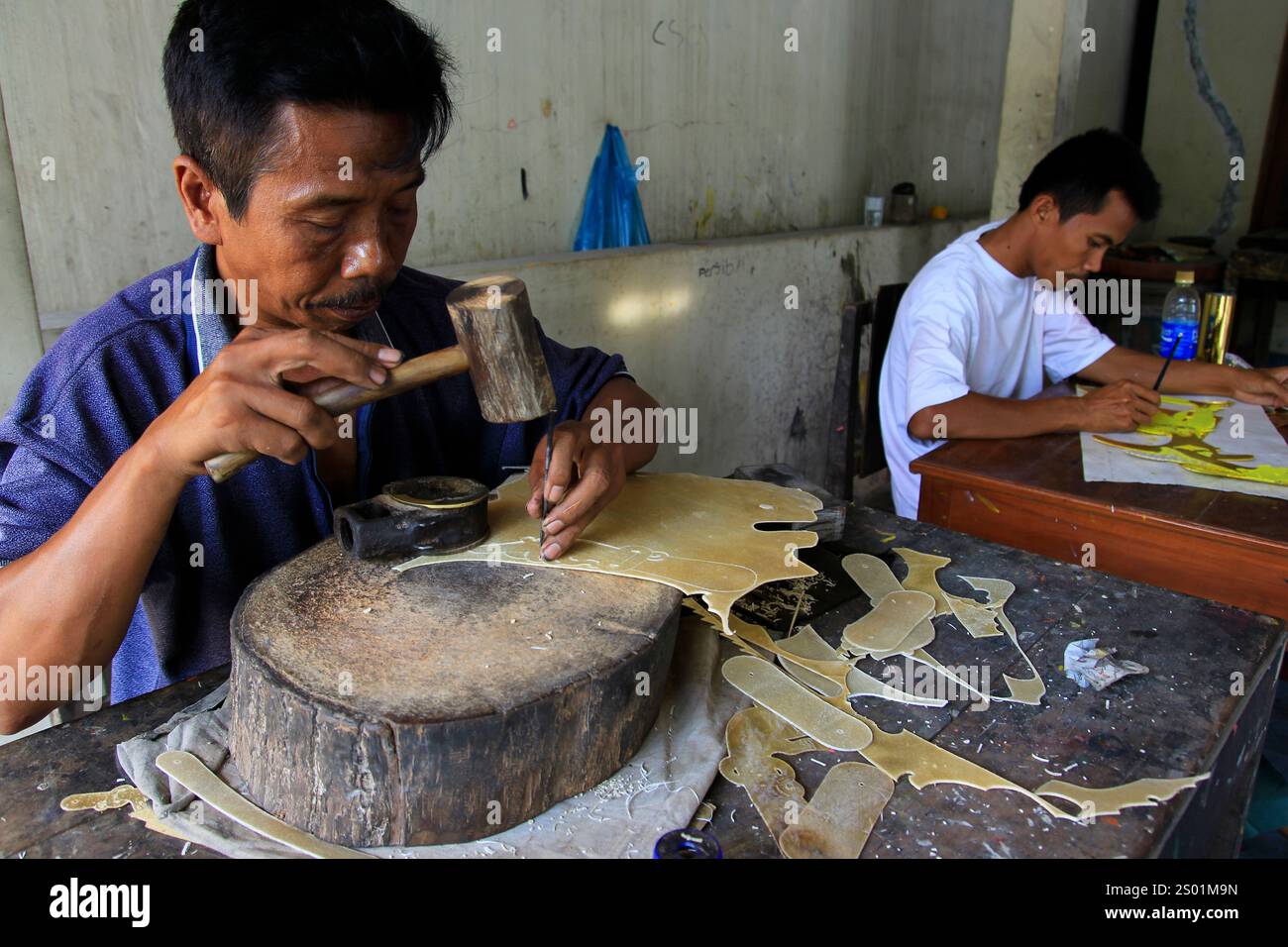 Wayang Kulit-Handwerker schnitzen das getrocknete Leder aus. Stockfoto