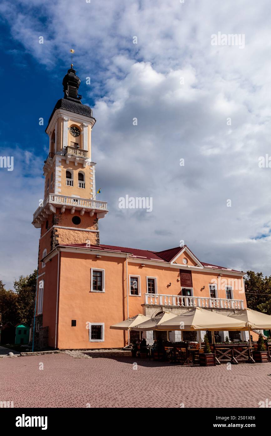 Ein großes Gebäude mit Uhrenturm und Markisen. Das Gebäude ist orange und hat viele Fenster Stockfoto