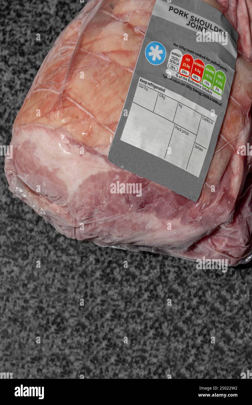 Gesaugtes, gefriertes Schweinefleisch mit einem Lebensmitteletikett. Auf schwarzem Granithintergrund Stockfoto