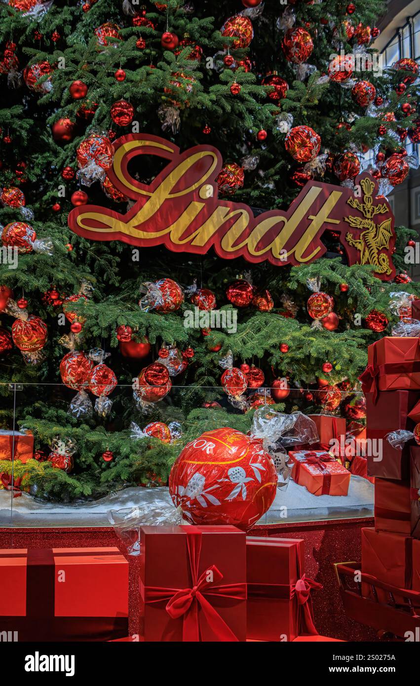 Zürich, Schweiz - 24. November 2024: Ikonischer Lindt-Weihnachtsbaum am SBB Hauptbahnhof Zürich mit roten Ornamenten und Schokoladendekorationen Stockfoto