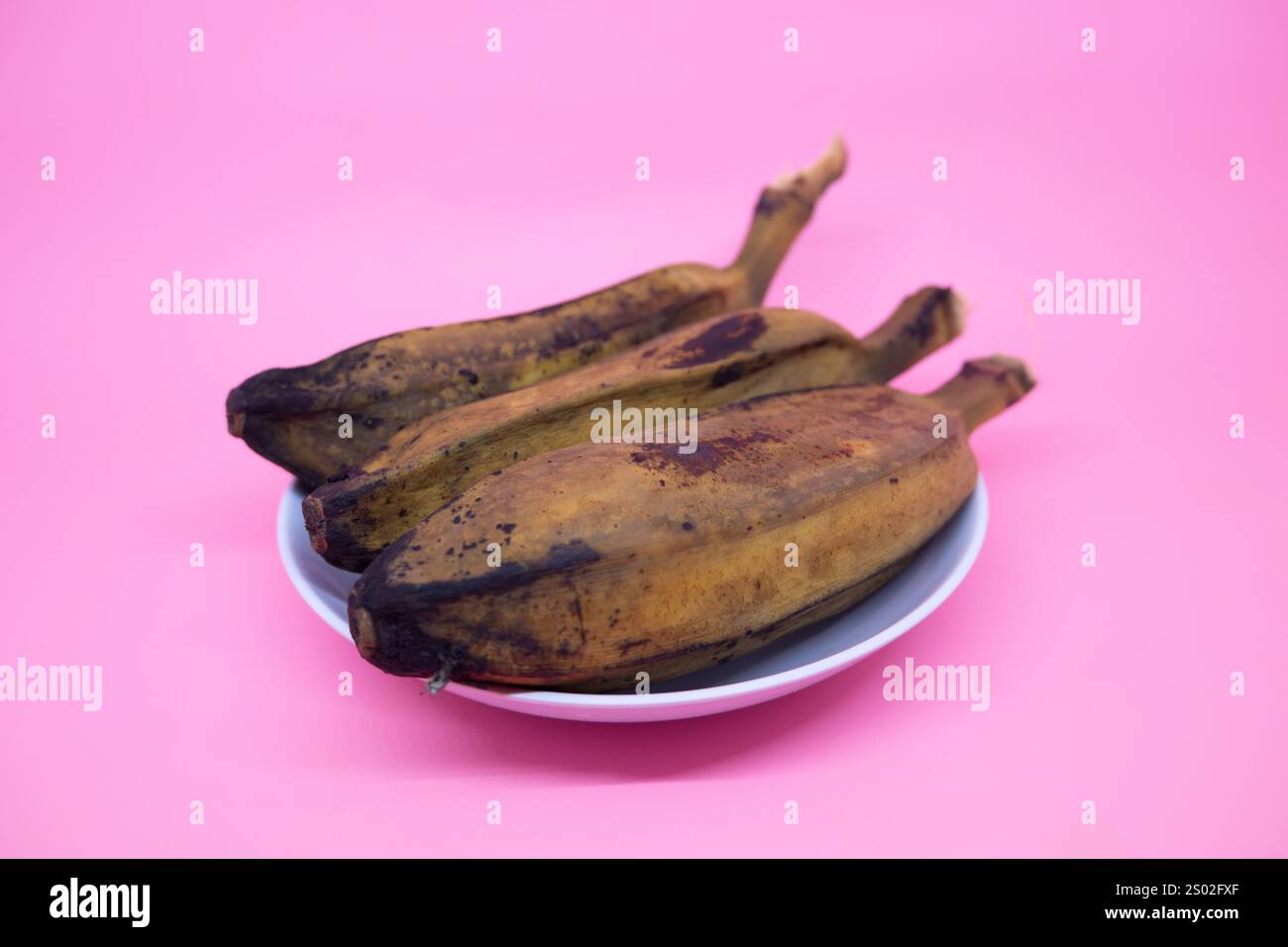 Köstliche und gesunde gekochte Bananen auf rosa Hintergrund Stockfoto