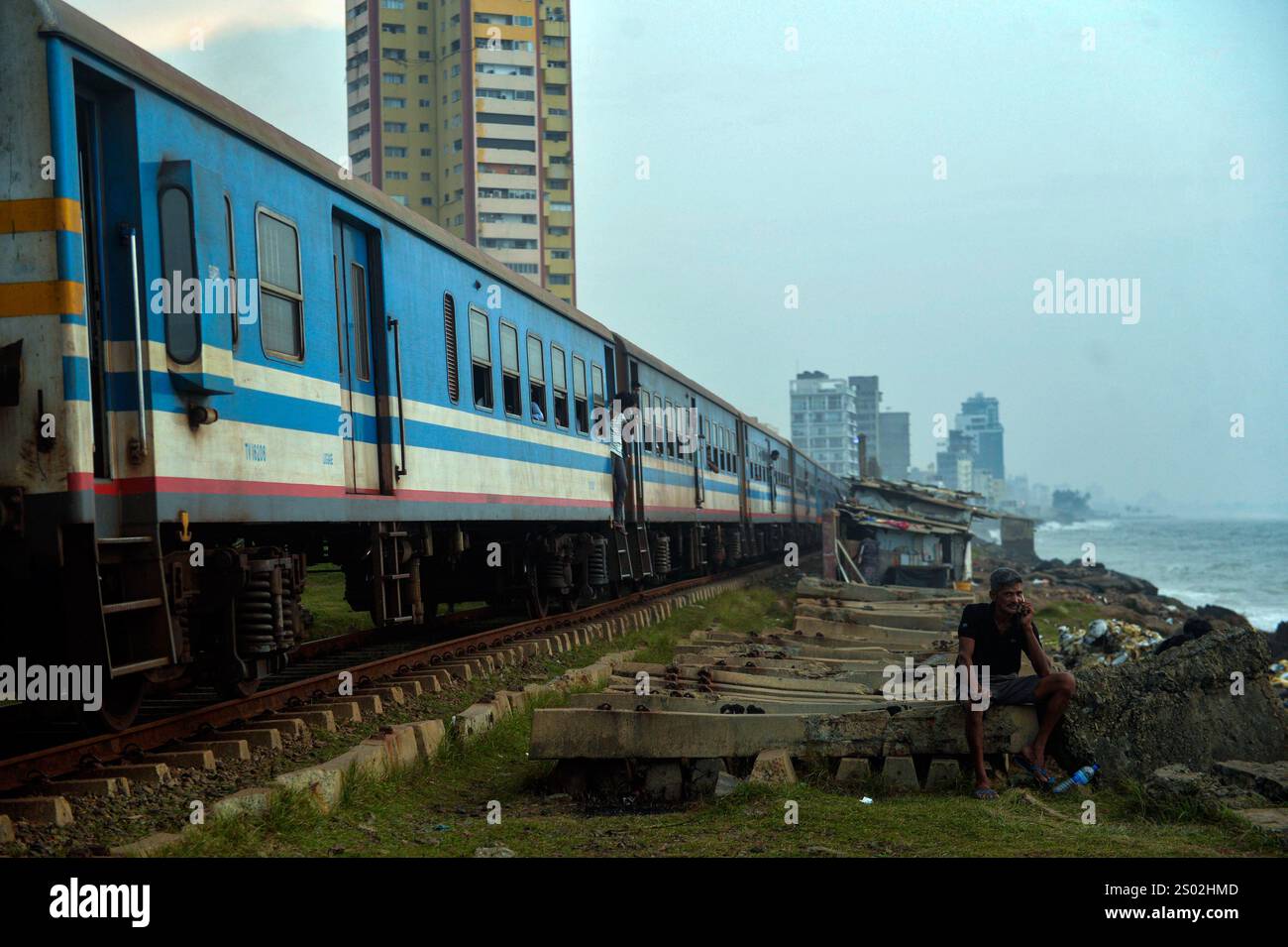 Colombo. Dezember 2024. Dieses Foto vom 18. Dezember 2024 zeigt einen Zug am Meer in Colombo, Sri Lanka. Die Küstenbahnlinie an der Westküste Sri Lankas und in der Nähe des Indischen Ozeans ist eine wichtige Eisenbahnlinie in diesem Inselstaat. Es ist auch eine berühmte Touristenattraktion, wo die geradlinige Küste, die Kutschen ohne Türen und der wunderschöne Meerblick während der gesamten Reise den Menschen ermöglichen, das einzigartige Erlebnis im Ceylon-Stil zu erleben. Quelle: Gayan Sameera/Xinhua/Alamy Live News Stockfoto