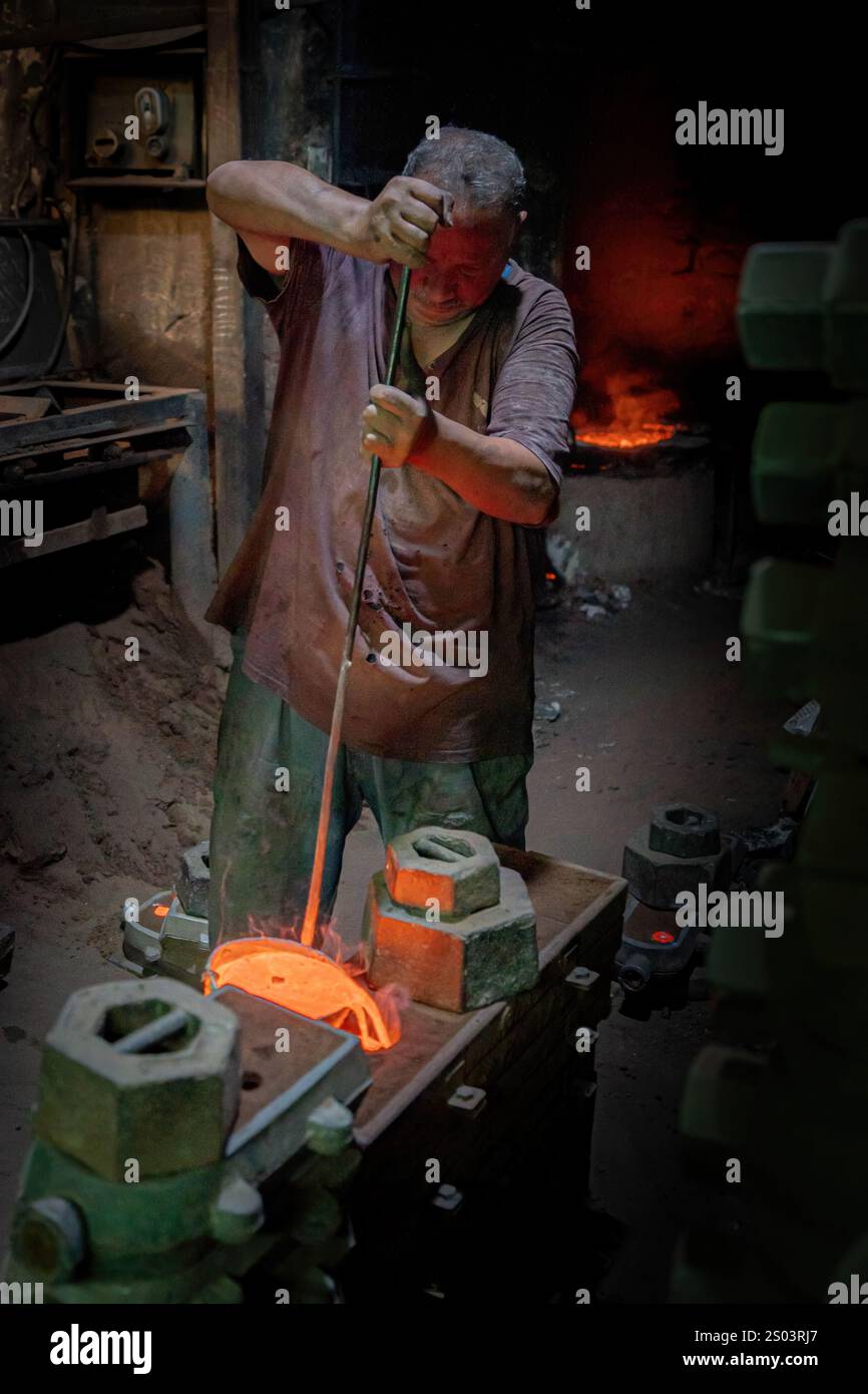 Ein Gießereiarbeiter in einer Werkstatt in Alexandria, Ägypten, der geschmolzenes Metall während eines Gießprozesses gekonnt handhabte. Ein großes Gründerbild Stockfoto