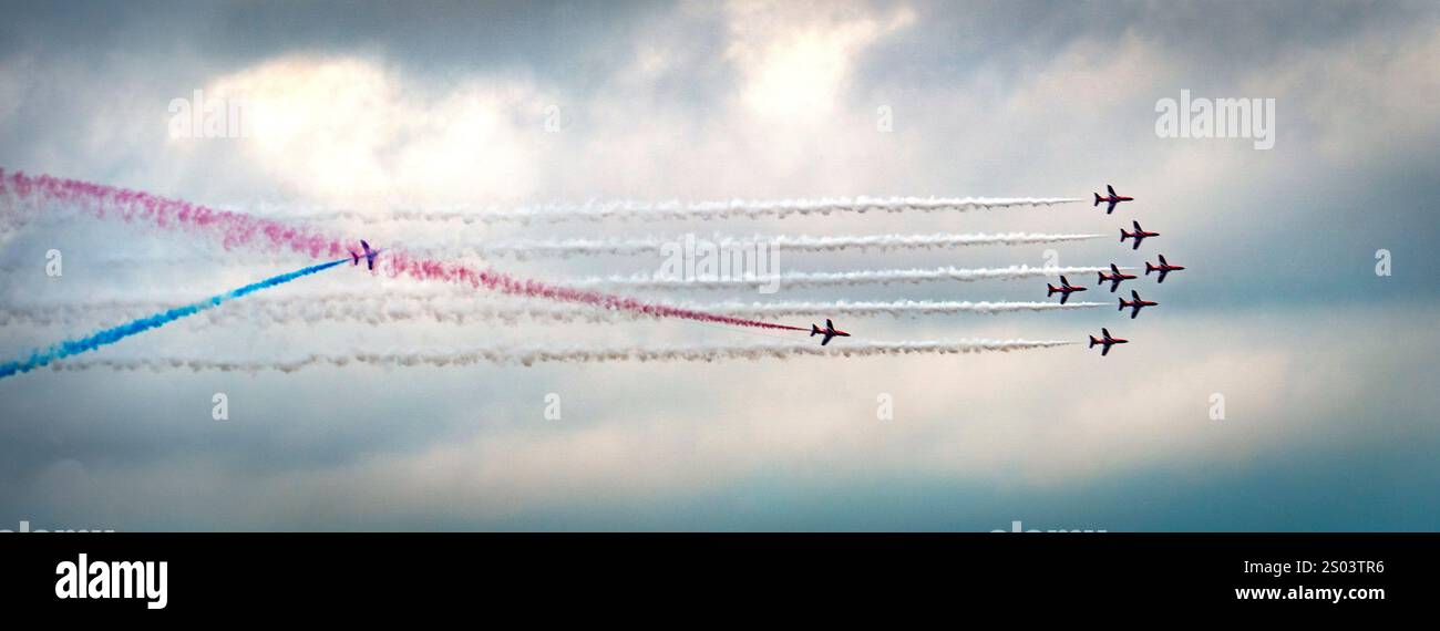 Luftbild mit Flugzeugen, die bunte Rauchspuren am Himmel hinterlassen. Die Ebenen sind in einem dynamischen Muster gegen einen Clou angeordnet Stockfoto