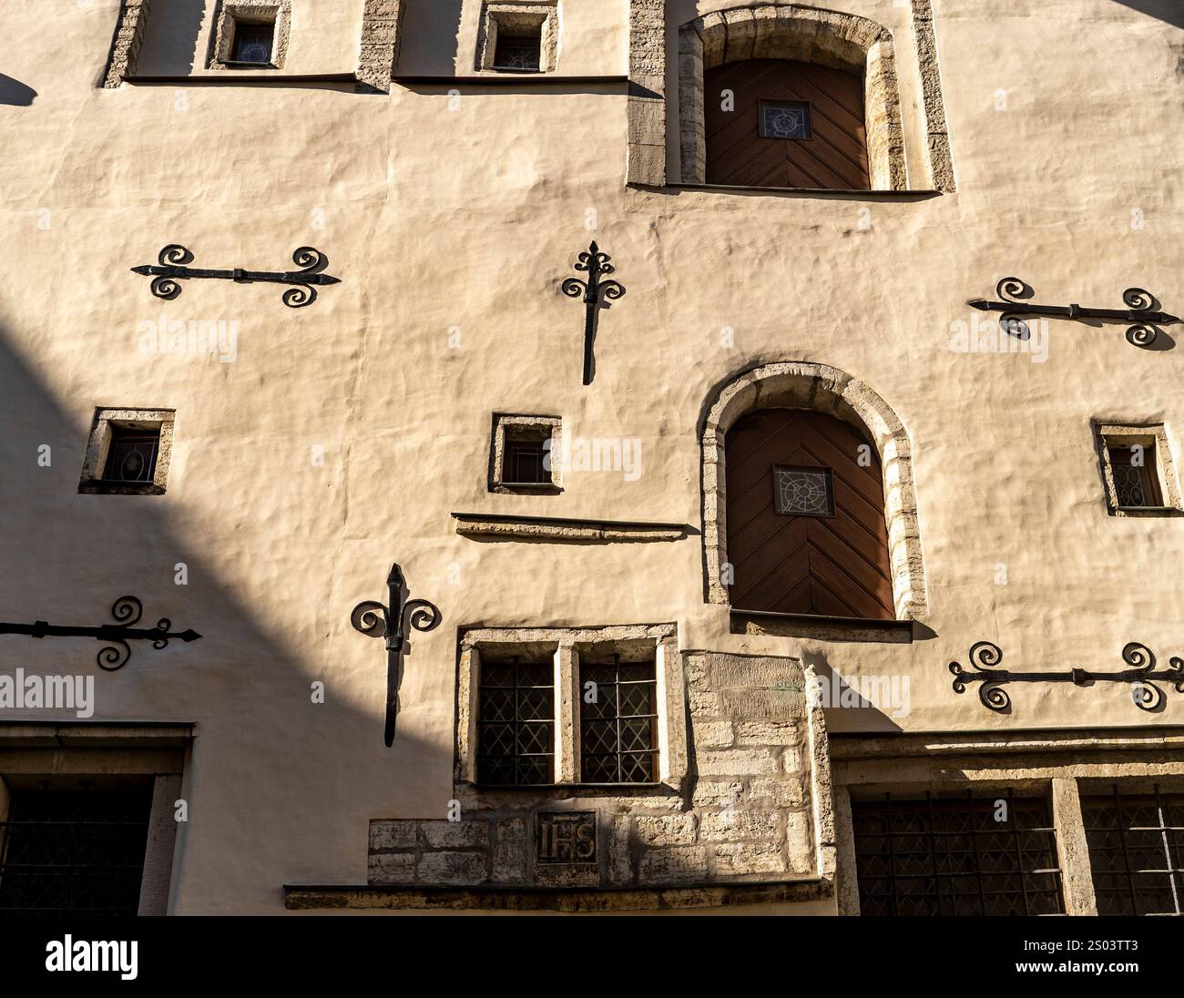 Eine strukturierte Wand mit dekorativen Elementen wie schmiedeeisernen Motiven und kleinen Fenstern aus nächster Nähe. Die Wand hat einen warmen, neutralen Ton, mit s Stockfoto
