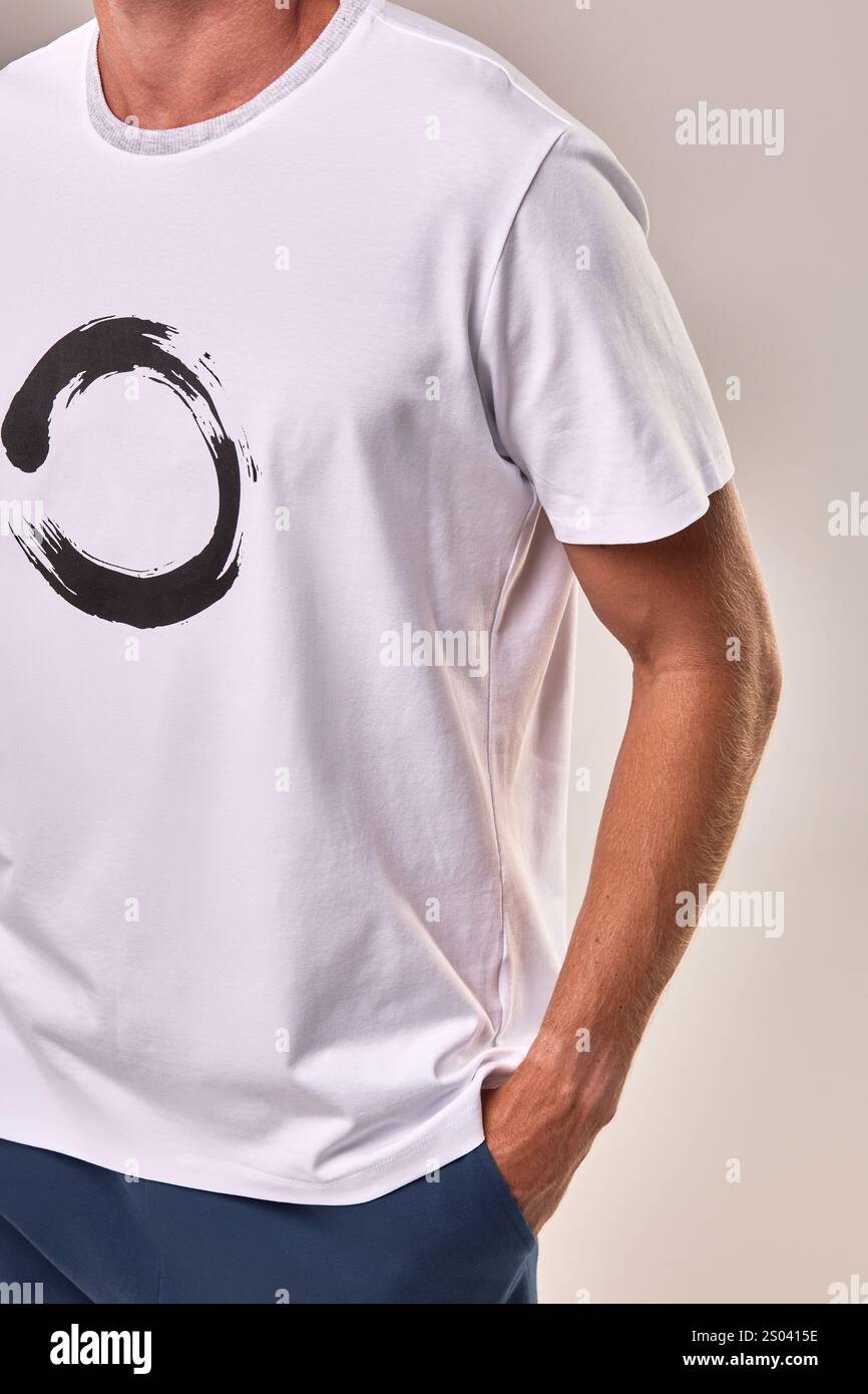 Nahaufnahme eines legeren Zen-T-Shirts mit einer Hand in der Tasche, minimalistisches weißes T-Shirt mit einem einzigartigen kreisförmigen Muster und Lifestyle-Konzept Stockfoto