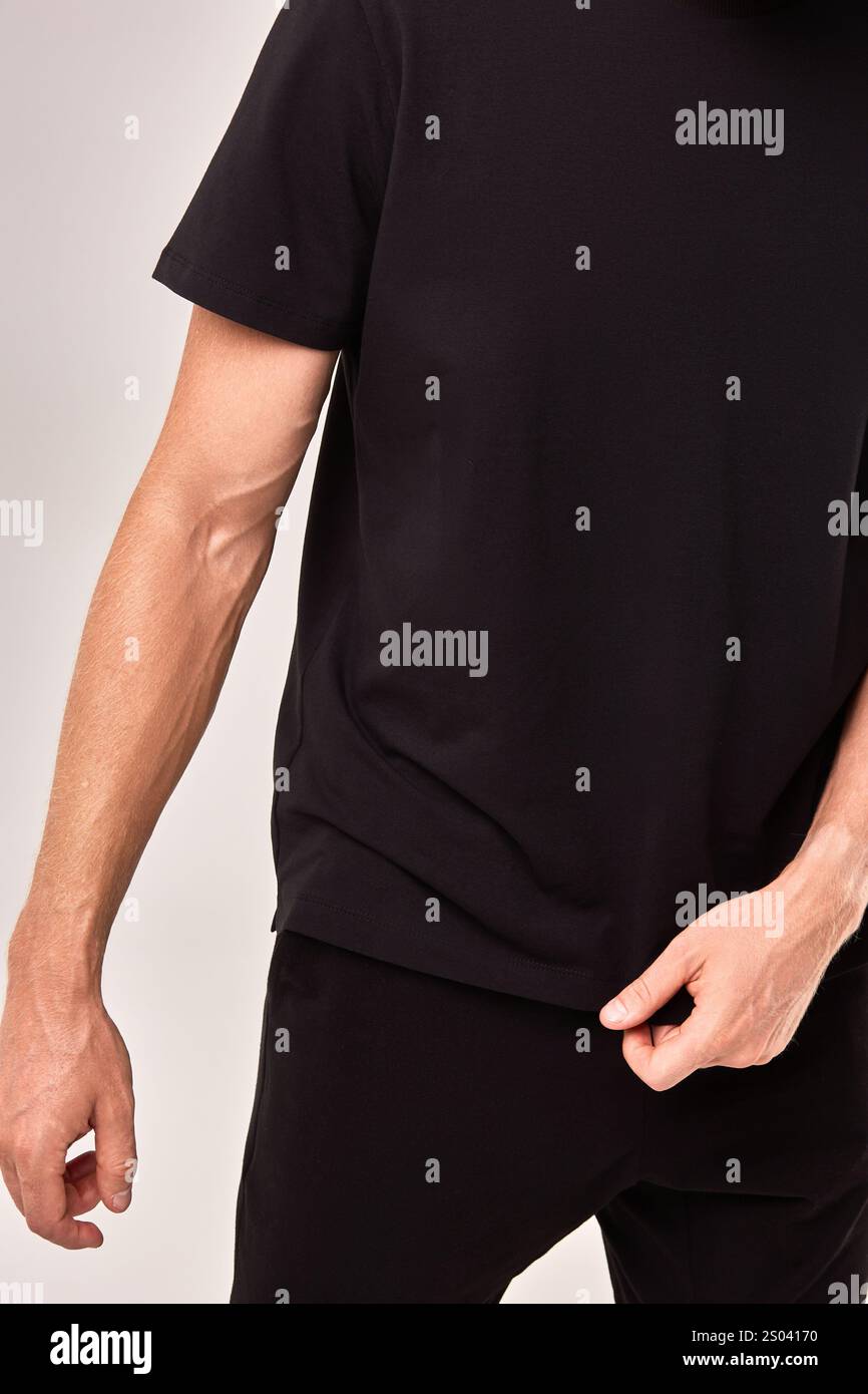 Person, die ein lässiges schwarzes T-Shirt trägt, betont einfache moderne Kleidung und ein alltägliches Modekonzept Stockfoto