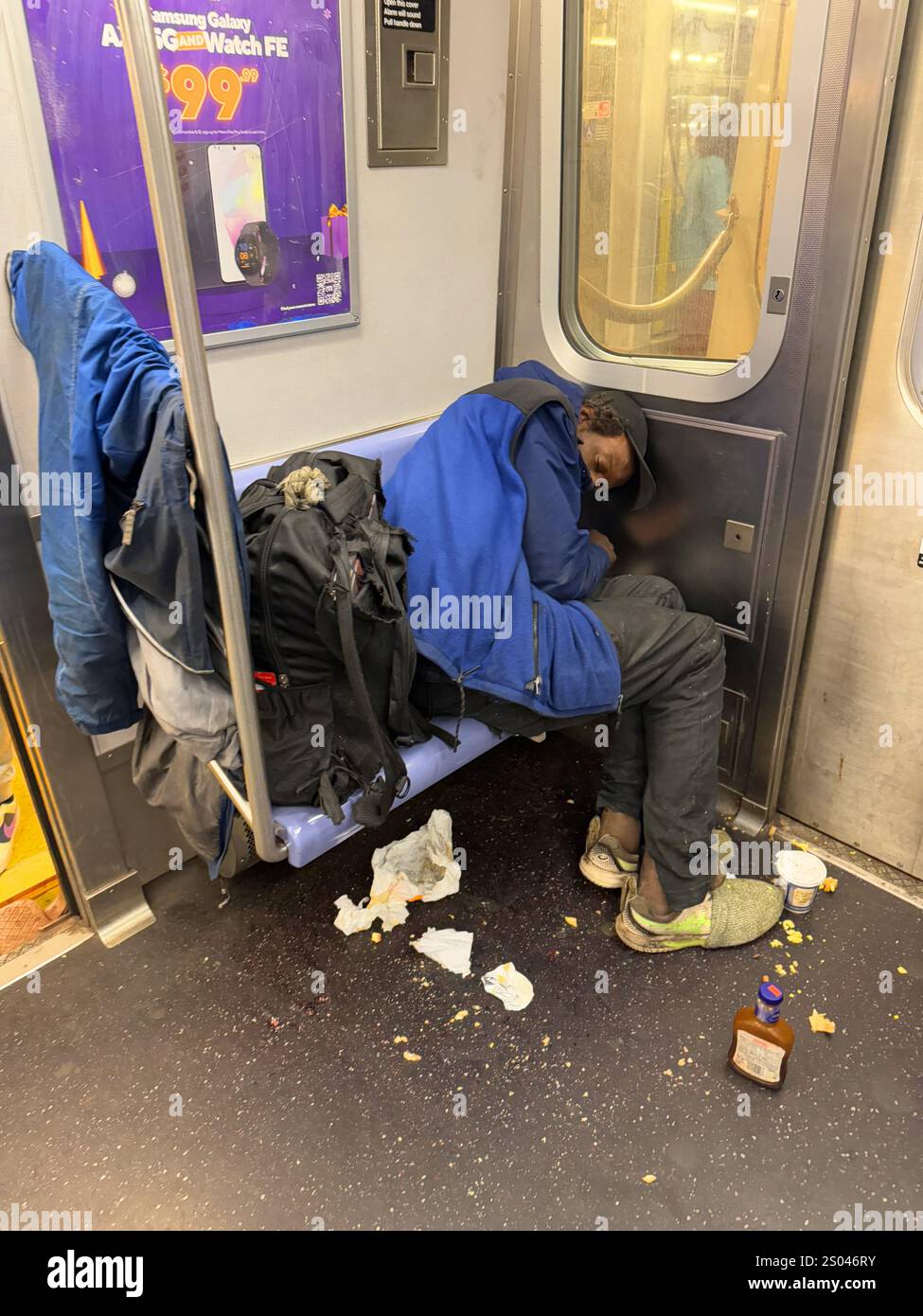 Ein ungepflegter Obdachloser schläft in einem New Yorker U-Bahn-Auto, auf dem Boden liegen die Reste einer Mahlzeit. Stockfoto