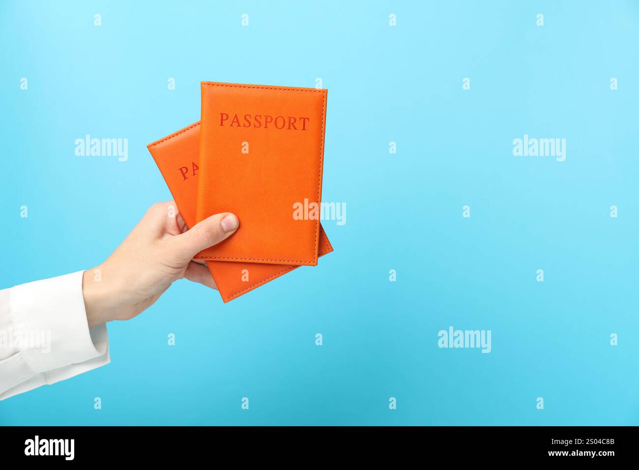 Frau, die Pässe in hellen Deckeln auf hellblauem Hintergrund hält, Nahaufnahme. Leerzeichen für Text Stockfoto