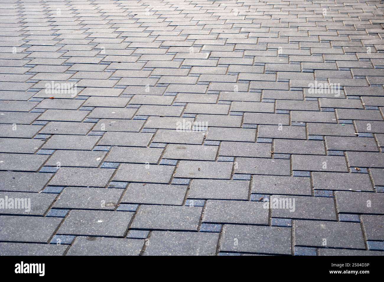Dieses Bild zeigt eine detaillierte Nahaufnahme eines Ziegelpflasters mit einem markanten diagonalen Muster, das visuelles Interesse und Textur verleiht Stockfoto