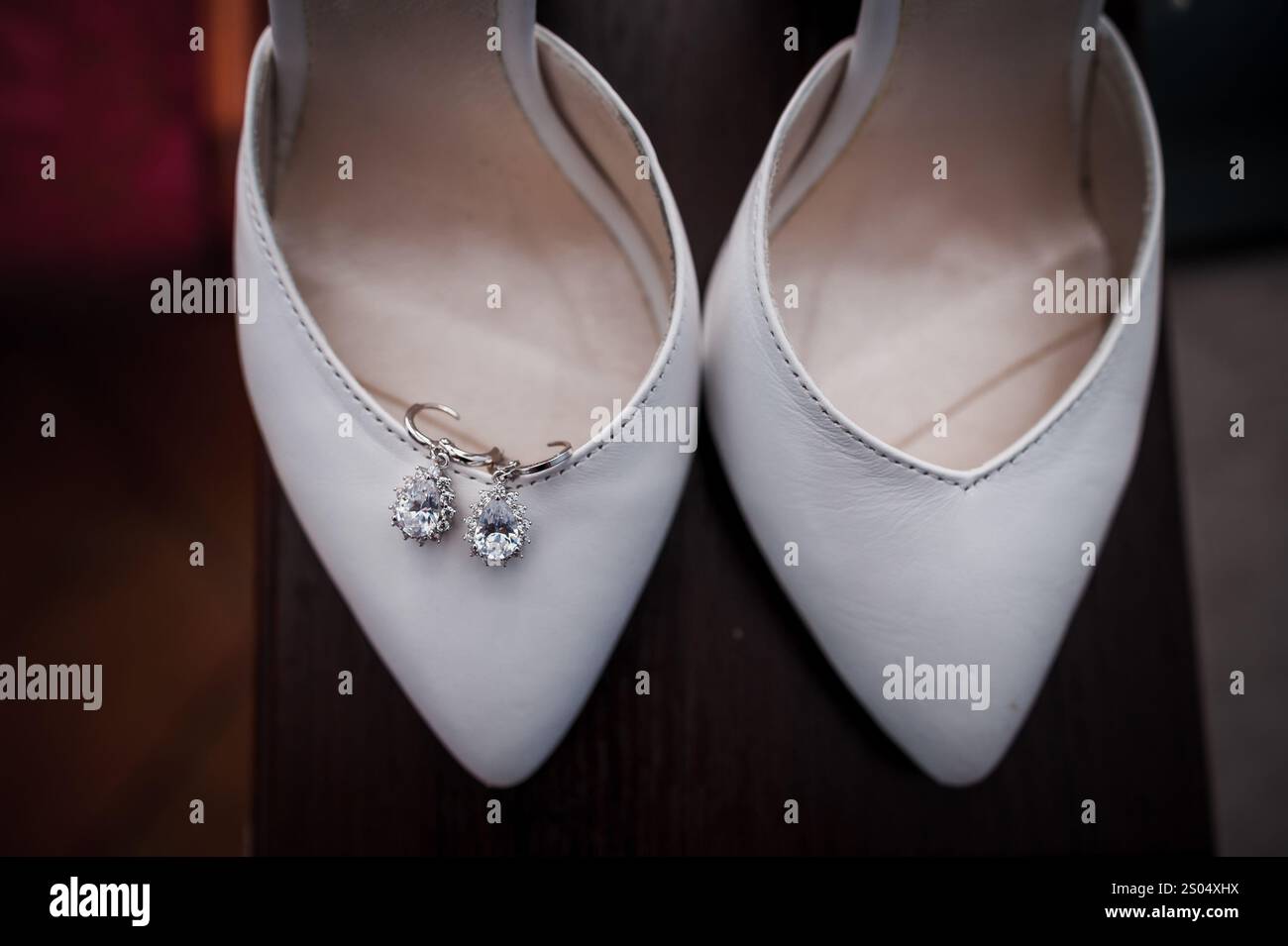 Elegante weiße Hochzeitsschuhe mit funkelnden Ohrringen. Stockfoto