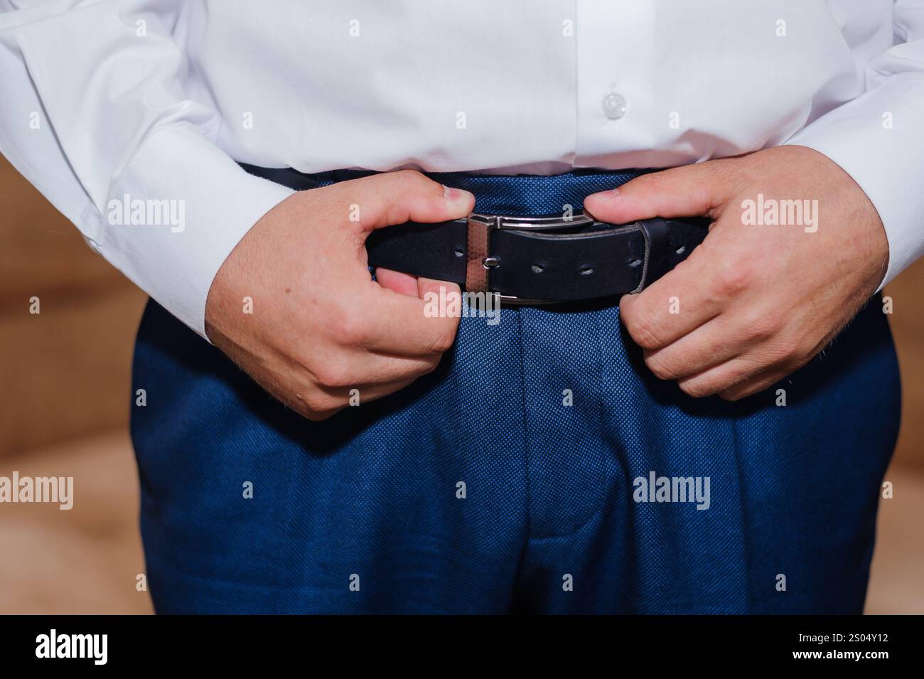 Elegante formelle Kleidung: Ein Mann, der seinen Gürtel anpasst. Stockfoto