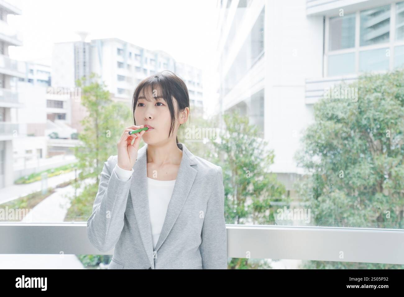 Eine junge Geschäftsfrau, die eine E-Zigarette raucht Stockfoto