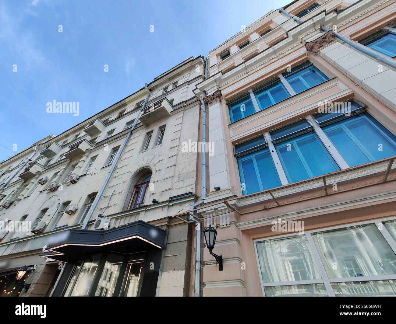 Großes mehrstöckiges Gebäude mit klassischer Fassade mit Bogenfenstern und modernen Verkaufsflächen im Erdgeschoss. Die Mischung aus traditionellem Stockfoto
