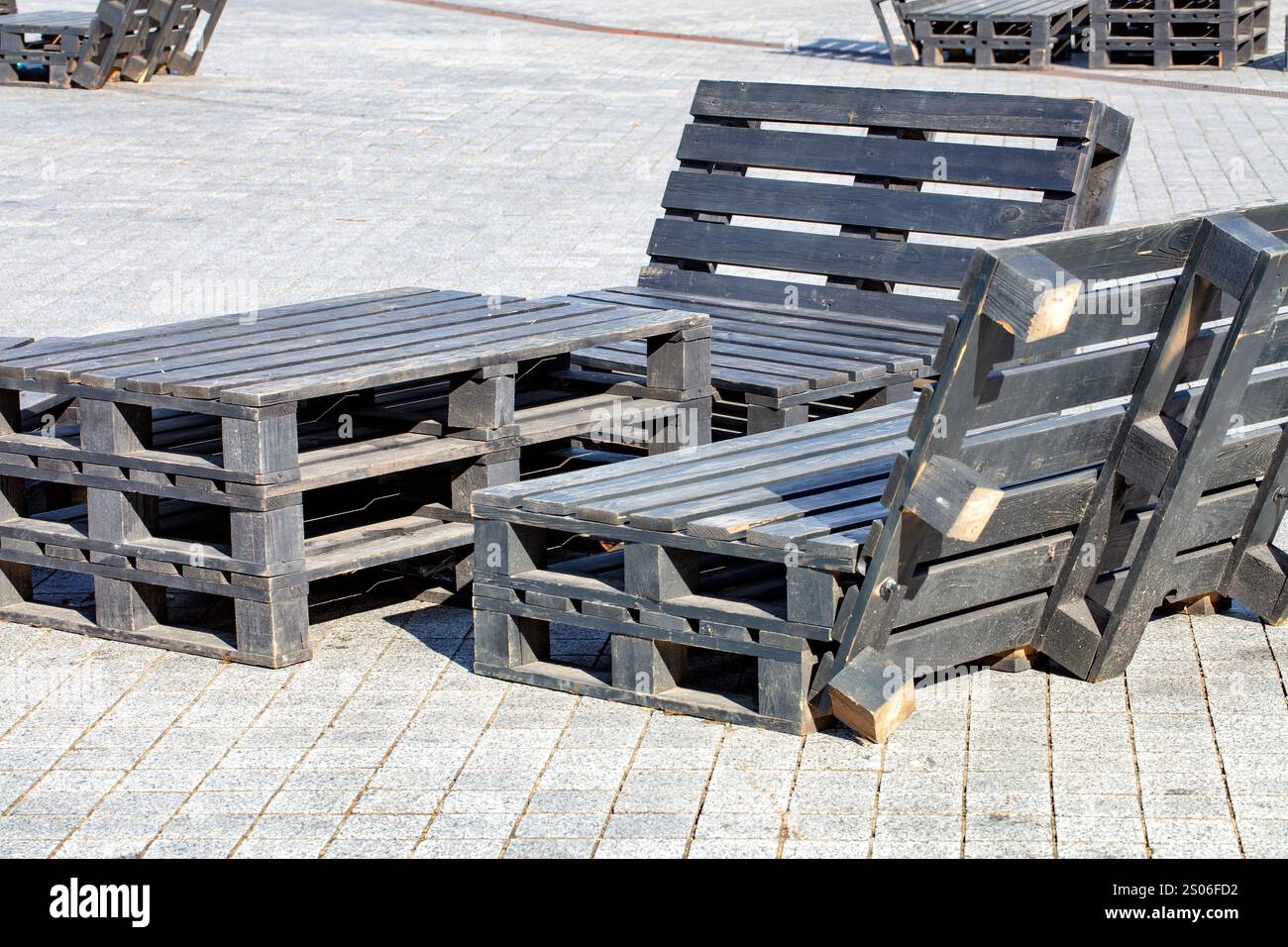 Kreative Sitzanordnung im Freien aus Holzpaletten in sonniger urbaner Umgebung Stockfoto
