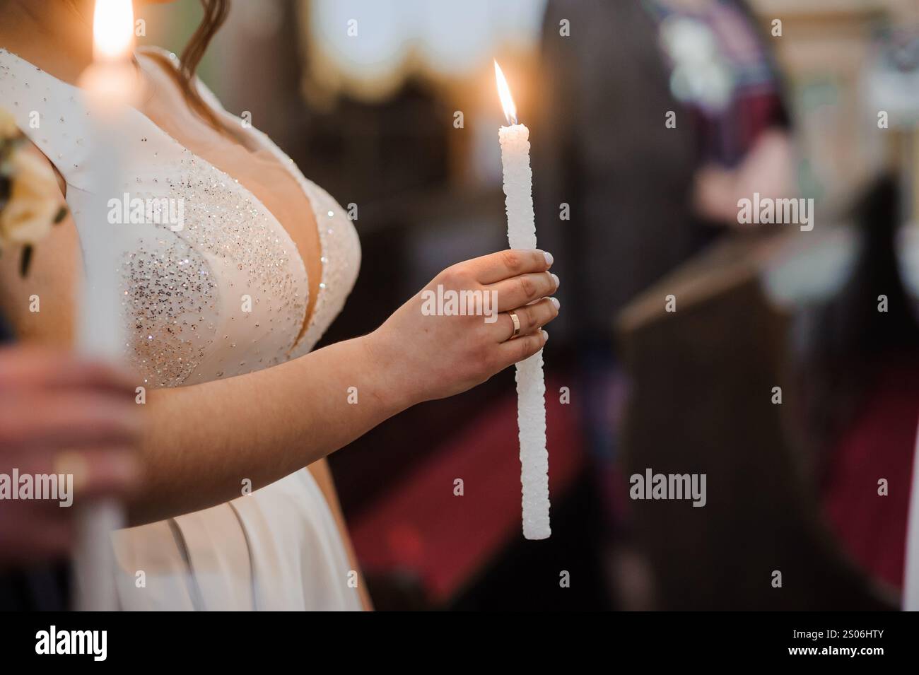 Elegante Braut hält eine Kerze in einer Zeremonie. Stockfoto