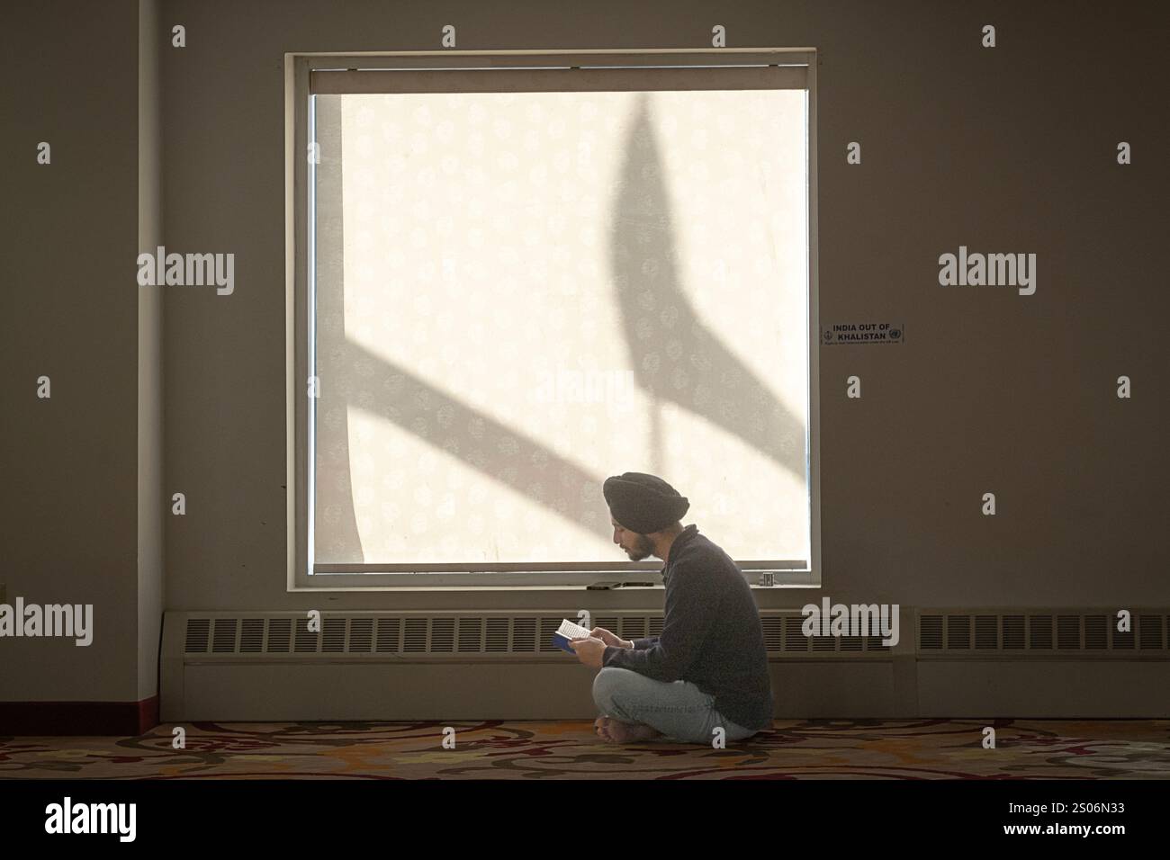 Ein Gläubiger Sikh-Anbeter liest Gebete vor einem Fenster der Sikh Cultural Society in South Richmond Hills, Queens, New York Stockfoto