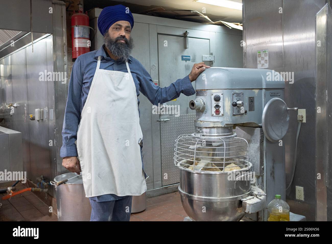 Porträt eines frommen Sikh-Mannes, der freiwillig in der Langar-Küche Teig für Roti-Brot zubereitet. In Richmond Hill, Queens, New York. Stockfoto