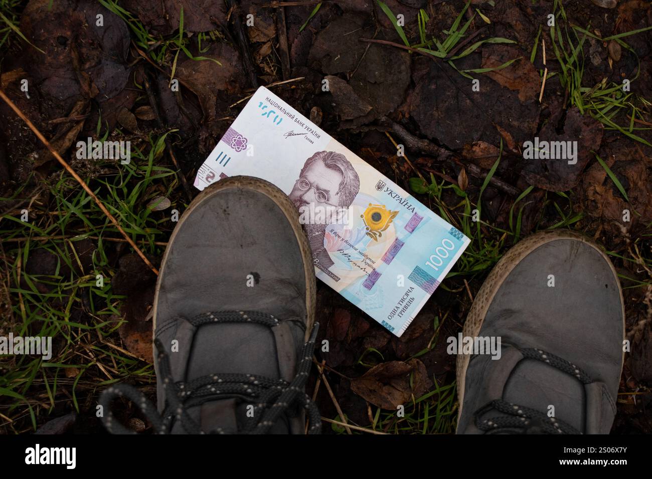 Ukrainische tausend Griwna liegt auf der Straße nahe den Füßen eines Mädchens im Winter in der Ukraine, finden Sie Geld Stockfoto