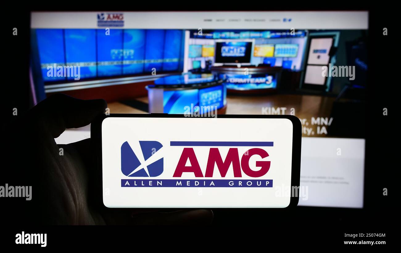 Stuttgart, Deutschland - 07.01.2024: Person mit Mobiltelefon mit Logo des US-Senders Allen Media Group (AMG) vor der Business-Website. Schwerpunkt auf dem Display des Telefons. Stockfoto