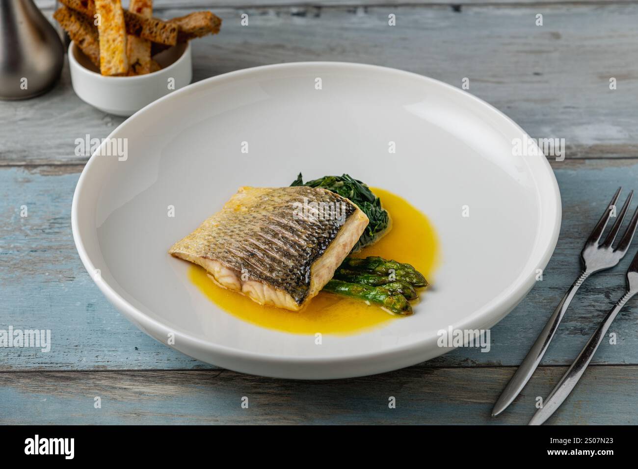 Gegrilltes Seebarschfilet mit Garnierungen in einem eleganten Restaurant Stockfoto