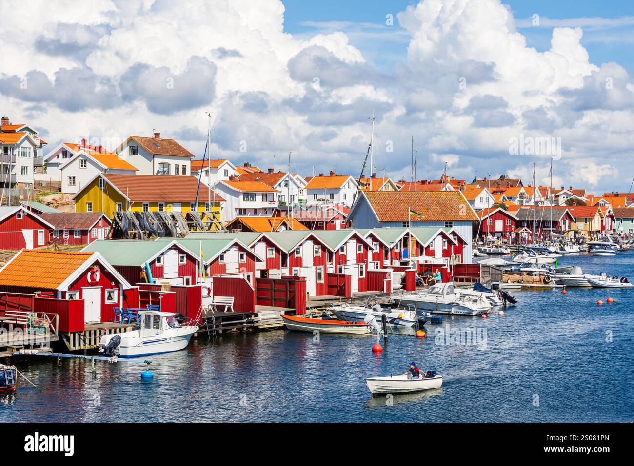 Stadtbild von Smögen, Schweden, mit alten rot bemalten Holzhäusern entlang des Meereskanals im historischen Zentrum des Dorfes an einem sonnigen Tag. Stockfoto