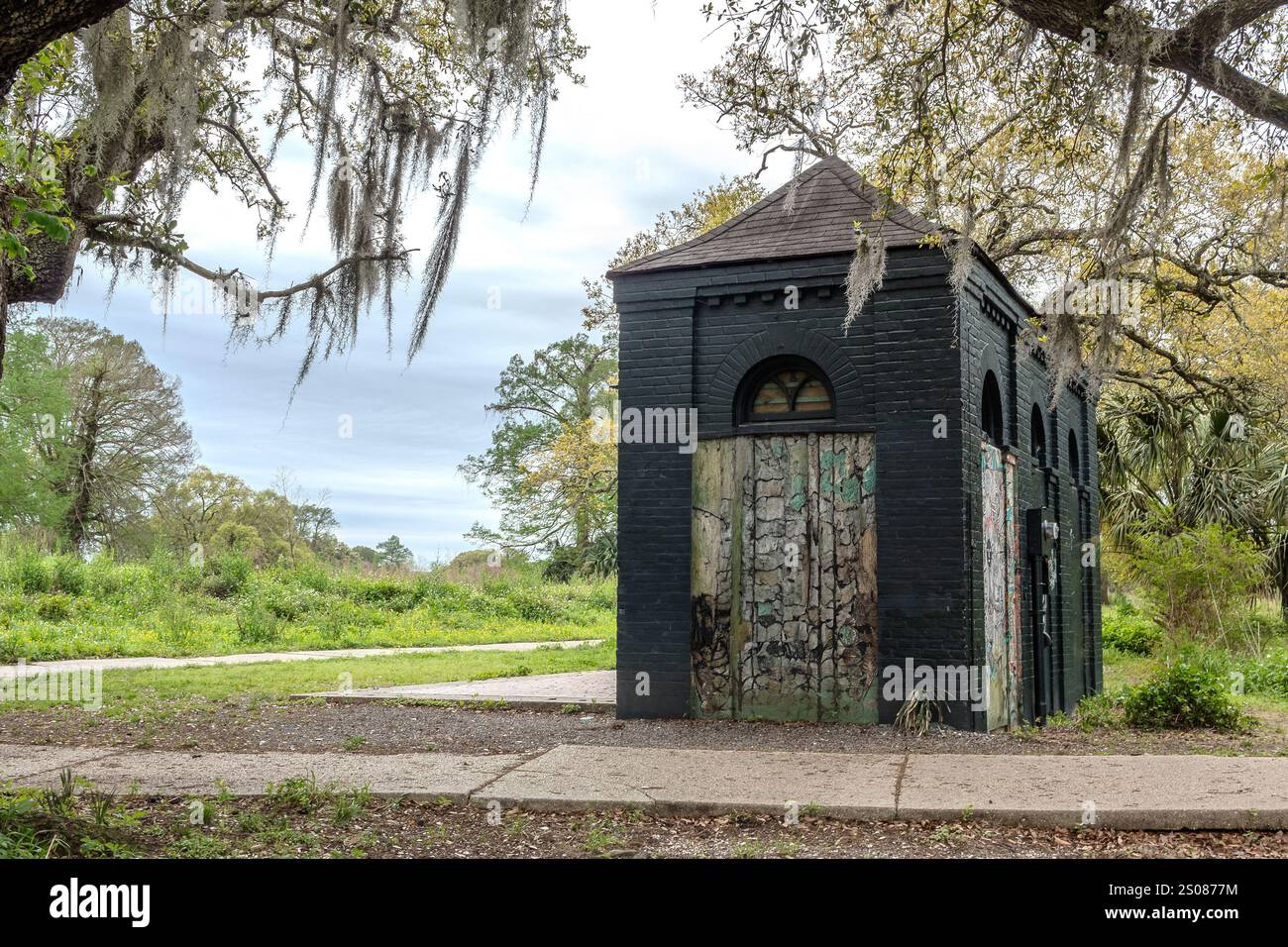 Holzgartenschuppen in einem Park, umgeben von Bäumen und Gras. Foto gemacht in New Orleans, Louisiana an einem bewölkten Tag Stockfoto
