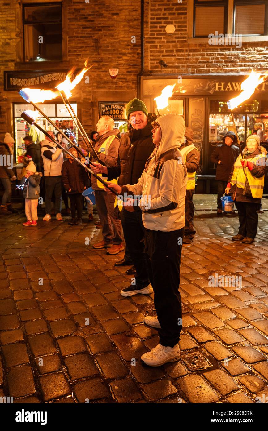 Haworth, West Yorkshire, Vereinigtes Königreich: Im Dezember findet jedes Jahr eine Fackelprozession statt. Flsming-Fackeln werden auf der steilen Main Street in Haworth Whi getragen Stockfoto
