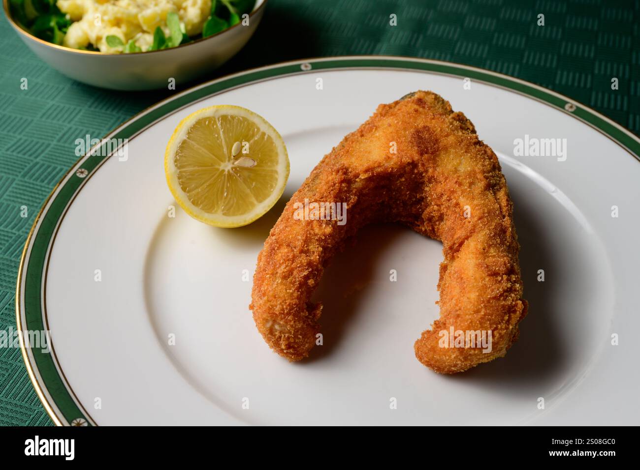 Paniertes und frittiertes Karpfensteak mit Mayonnaise-Kartoffelsalat und einer Zitrone Stockfoto