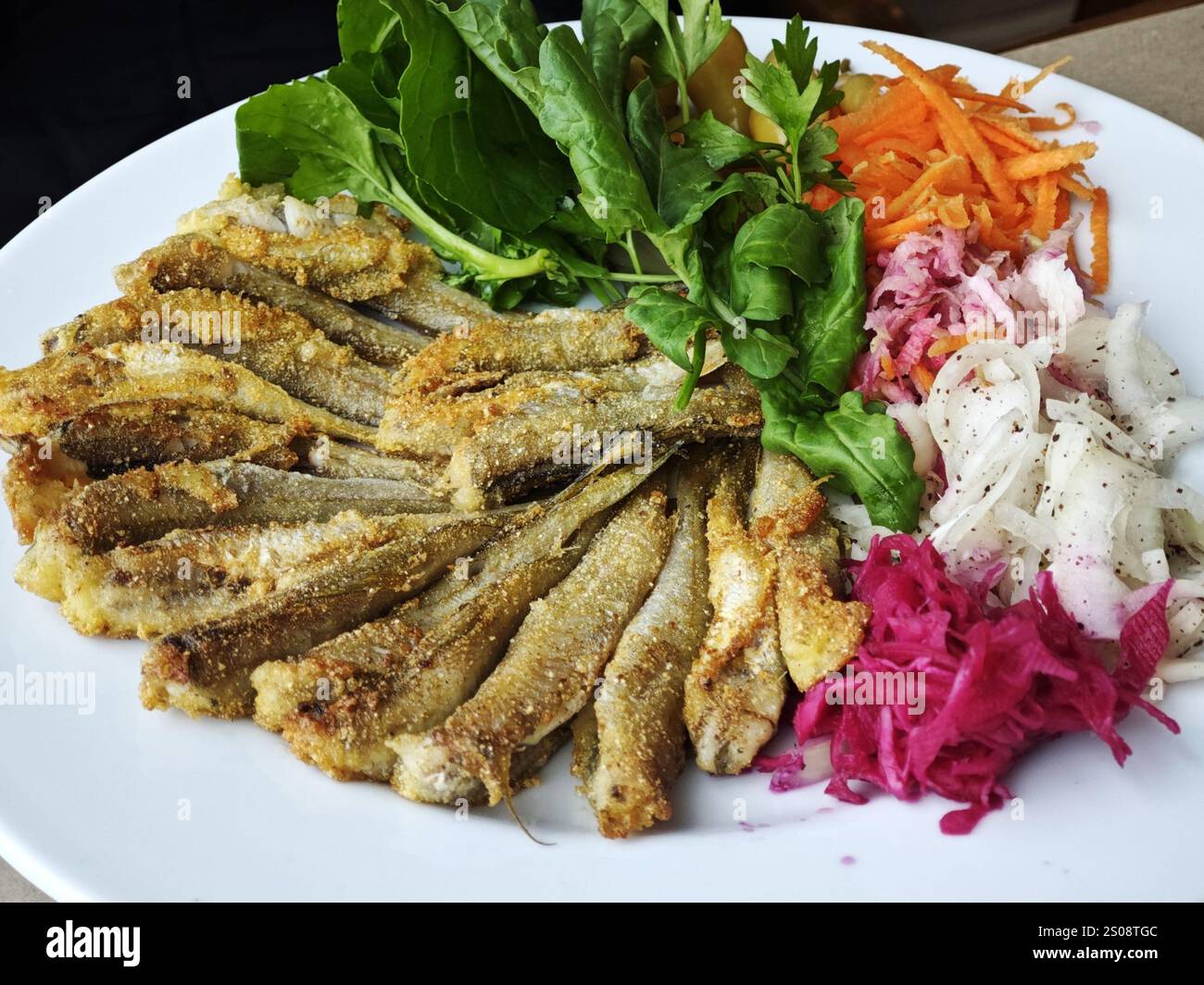 Hamsi Tava ist ein traditionelles türkisches Balık Meeresfrüchte-Gericht aus Hamsi oder frittierten Sardellen, serviert mit Salat, Zwiebeln und Petersilie Stockfoto